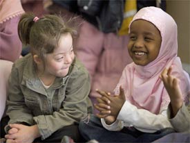 Girl with learning disabilities and young Muslim girl laughing together